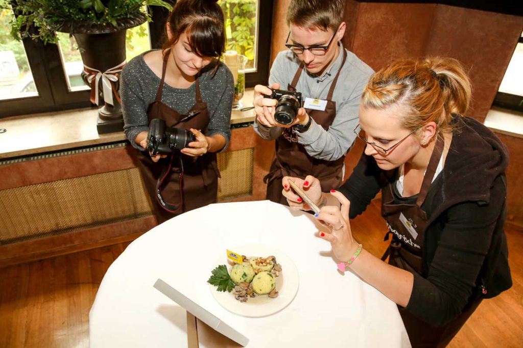 Foodblogger beim Fotografieren von einem Teller mit Knödeln, die dabei die Tipps rund um Foodfotos mit dem Smartphone beachten.