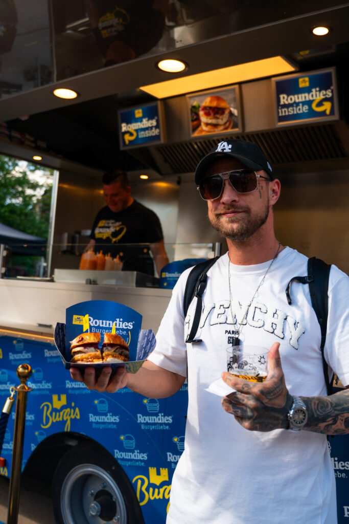 Mit Burger und Bier in der Hand bereit zum Probieren